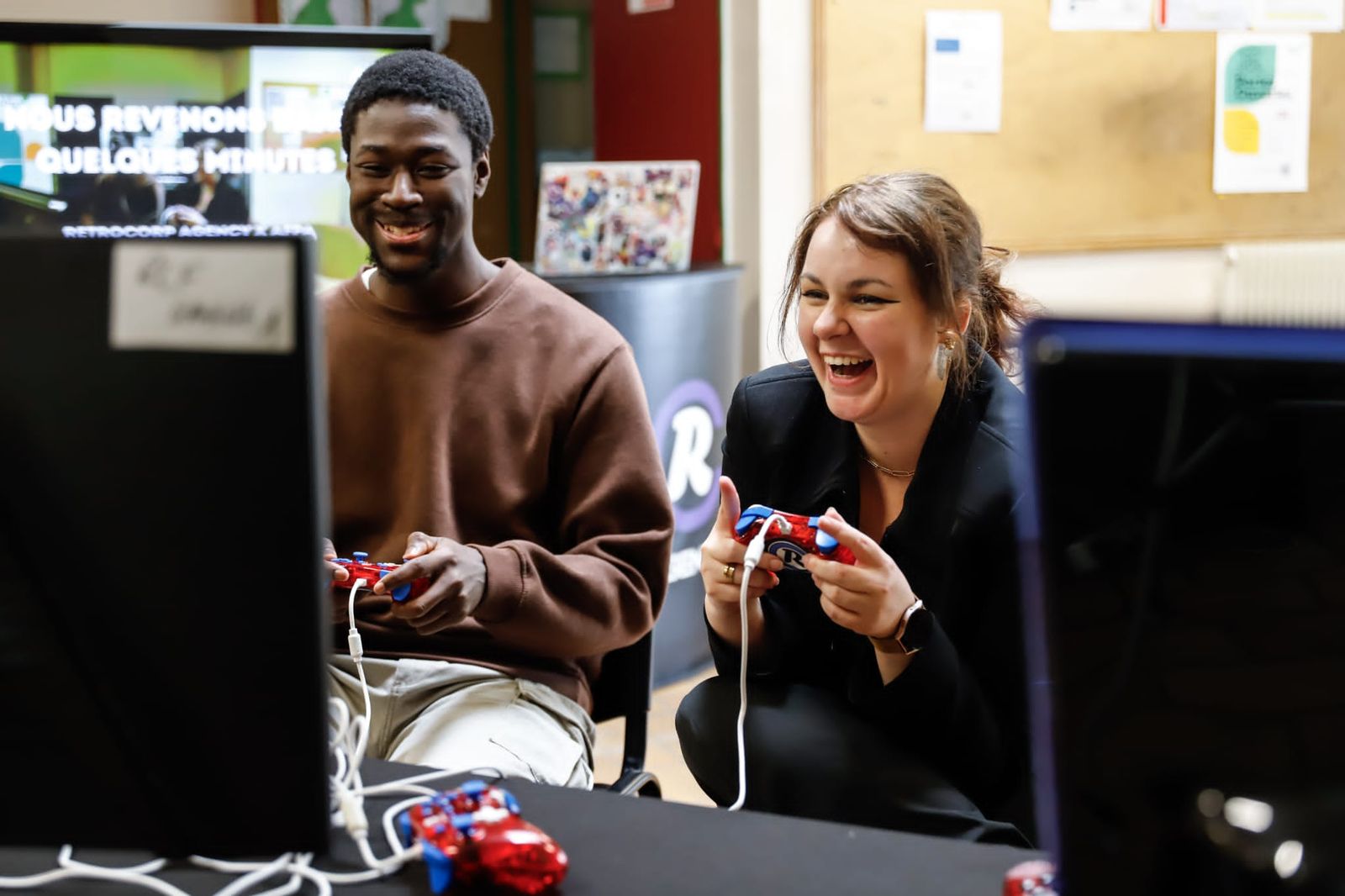 Un candidat et une employeuse rient pendant une partie de jeu vidéo lors d'un Job Quest